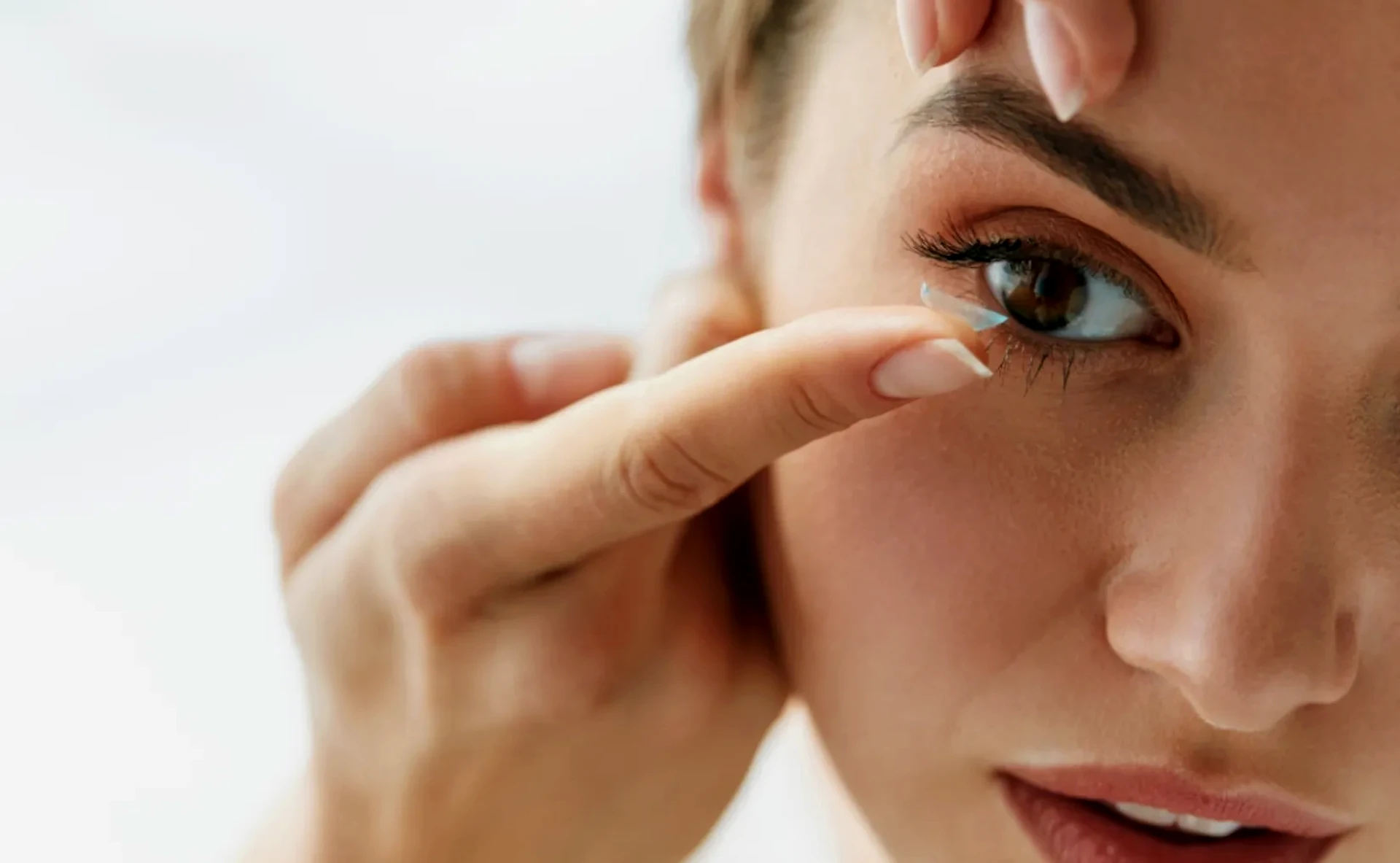 Frau setzt eine Kontaktlinse ein – Perfekte Sicht mit individuell angepassten Kontaktlinsen.